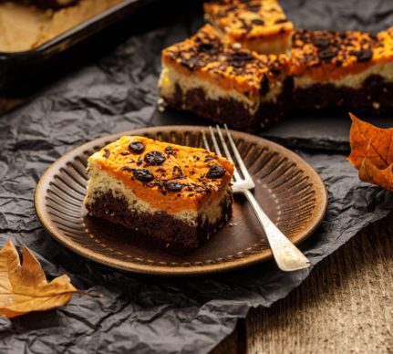 Porții de brownie cu brânză și dovleac decorate cu bănuți de ciocolată