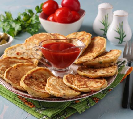 Mini pizza pancakes pe un platou cu un bol de ketchup la mijloc