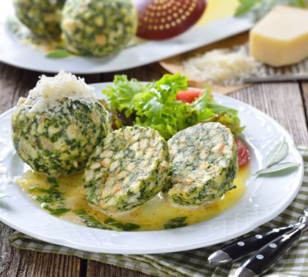 Chiftele de spanac cu pâine și parmezan, în sos de unt, pe două farfurii